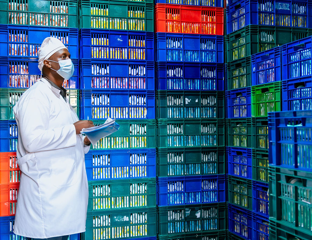 An Ishyo Foods quality inspector beside stacked crates of packaged yoghurt