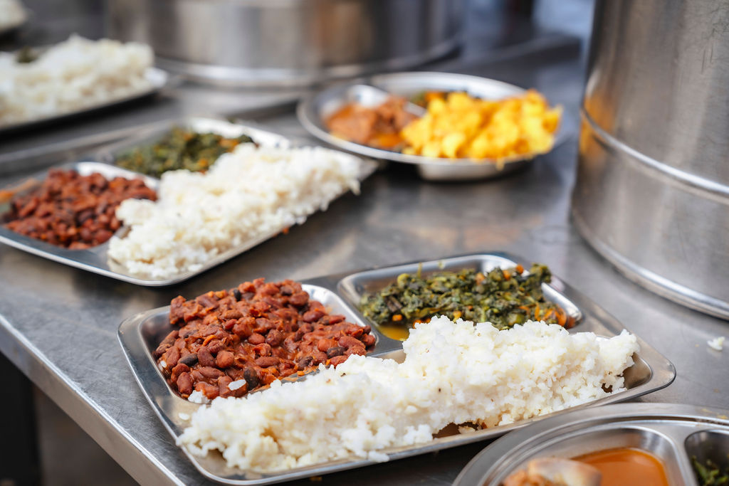 Trays of rice, greens and protein prepared for serving